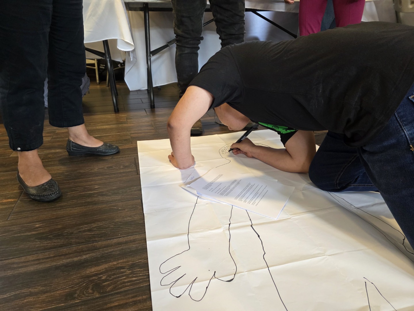 ¿Cómo se conforman los estatutos de mi asociación? Uno de los espacios de trabajo durante el taller fue el elaborar una silueta de una persona para identificar las partes medulares de los estatutos de las asociaciones. Texto alternativo: Persona traza su silueta sobre papel en el suelo como parte de una actividad reflexiva.