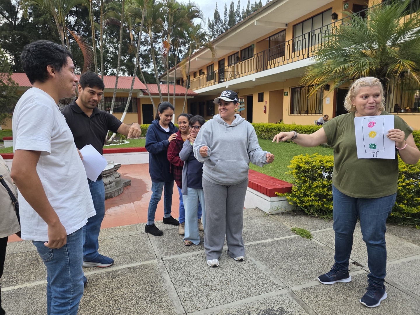 Dramatizaciones Una de las actividades desarrolladas fue el dramatizar una sociedad donde se promueven y practican los derechos de las personas con discapacidad. Texto alternativo: Grupo de siete personas interactúa en un patio. Una mujer sostiene una hoja con círculos rojo, amarillo y verde como herramienta de la actividad
